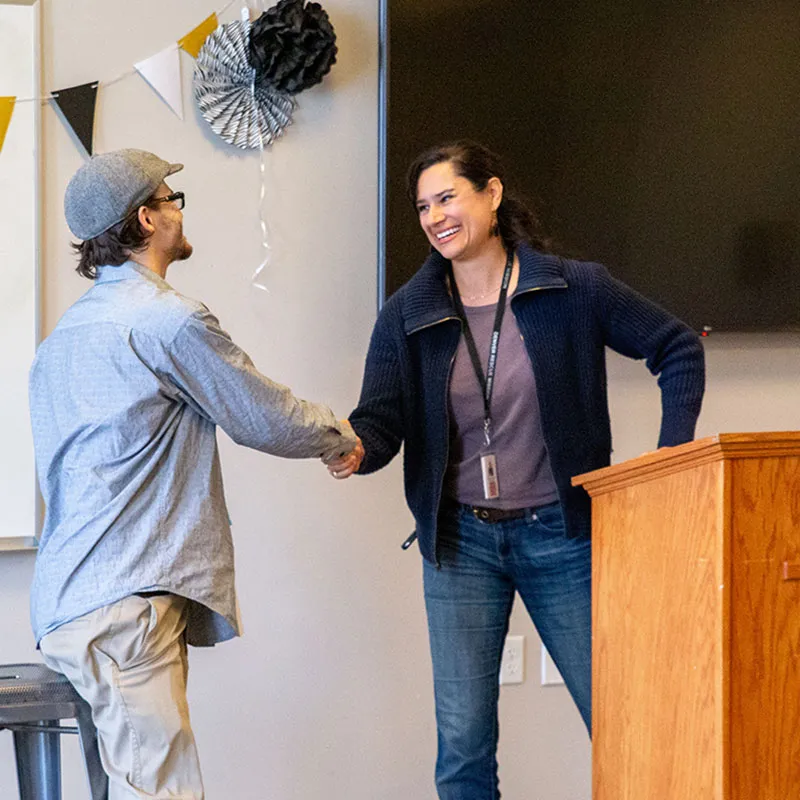 Rachel Lopez shaking hands with program graduate.