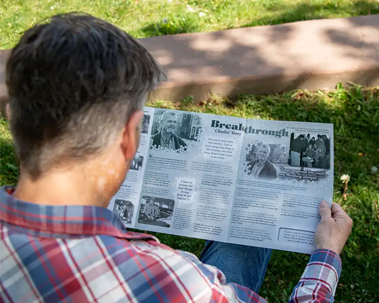 Charles junior look at Charles senior's Changing Lives Newsletter